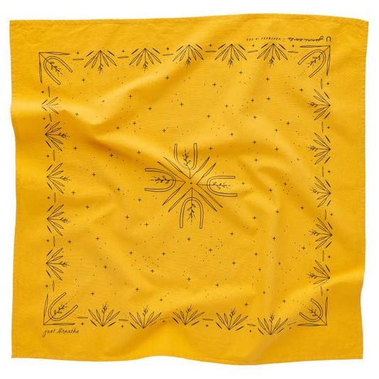 The "Just Breathe" bandana by Jenni Earle features a yellow fabric with black geometric and botanical designs along the border and center, displayed with a gently wrinkled look.