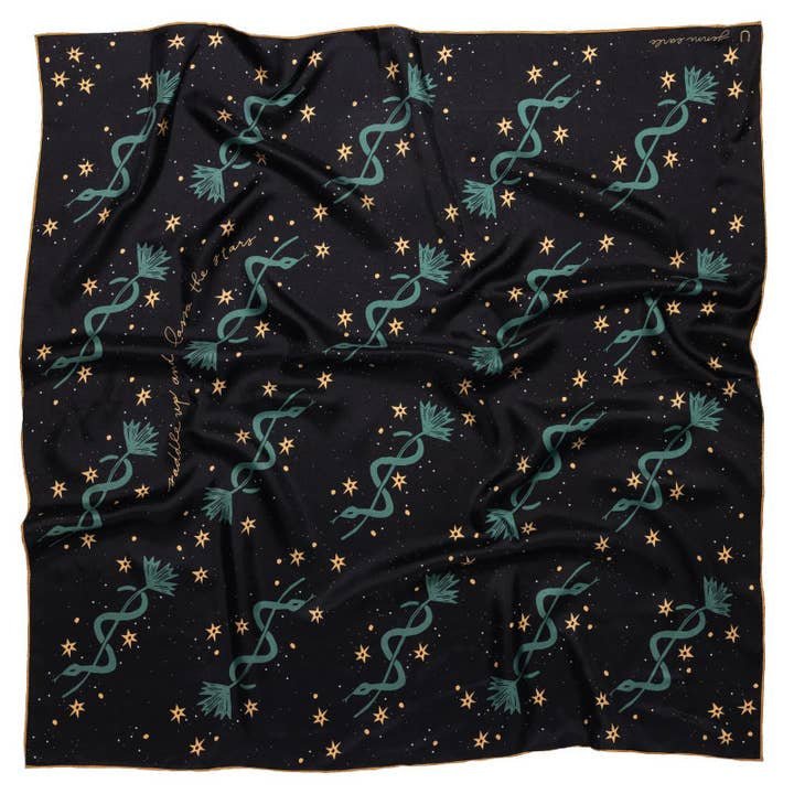 The “Lasso The Stars” bandana by Jenni Earle is a black, 100% silk scarf adorned with green botanical designs and gold stars—a stylish and elegant accessory, perfect for gifting.