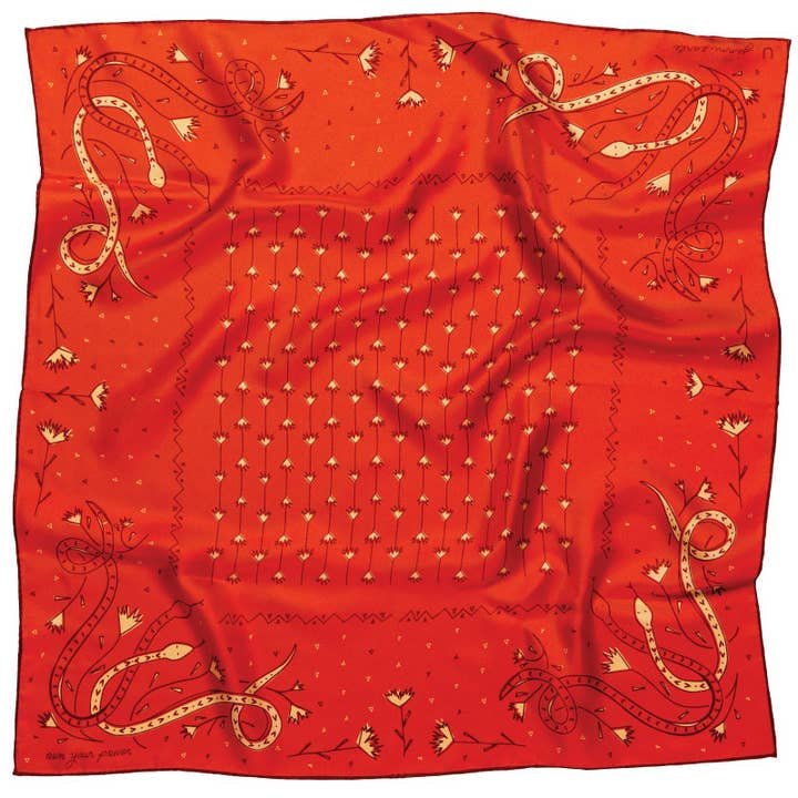 The "Bandana | Own Your Power Silk" by Jenni Earle is a red silk scarf featuring central floral motifs and stylized corner snakes, framed with decorative details—ideal as a holiday gift or a stylish bandana.
