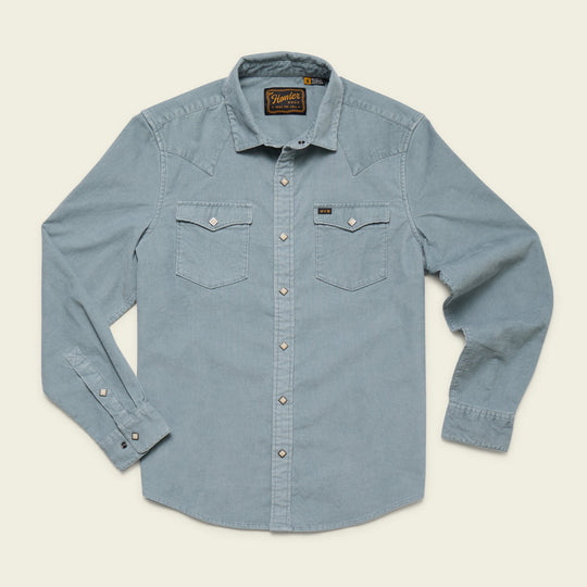 The Howler Brothers Banning Corduroy is a light blue, long-sleeve western shirt with diamond pearl snaps, two flap chest pockets, and a collar, shown laid flat on a neutral background.