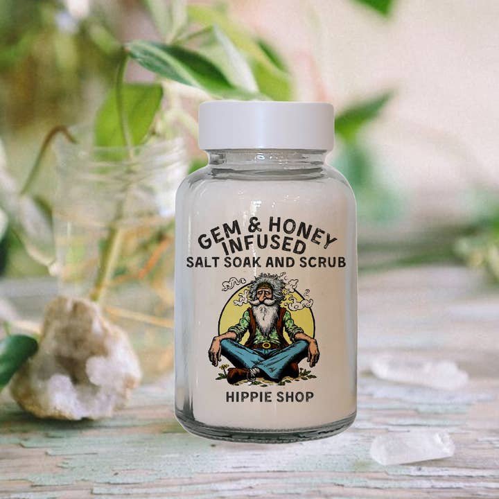 A clear jar labeled "Bath Soak | Nag Champa | Wild Yonder Botanicals" from Wild Yonder Botanicals sits on a table with crystals and greenery, featuring an illustrated bearded man and enriched with organic botanical extracts.