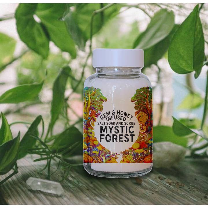The Bath Soak | Mystic Forest by Wild Yonder Botanicals sits among green leaves and crystals, evoking the calm of forest bathing with soothing hinoki notes in this luxurious gem and honey infused salt soak.