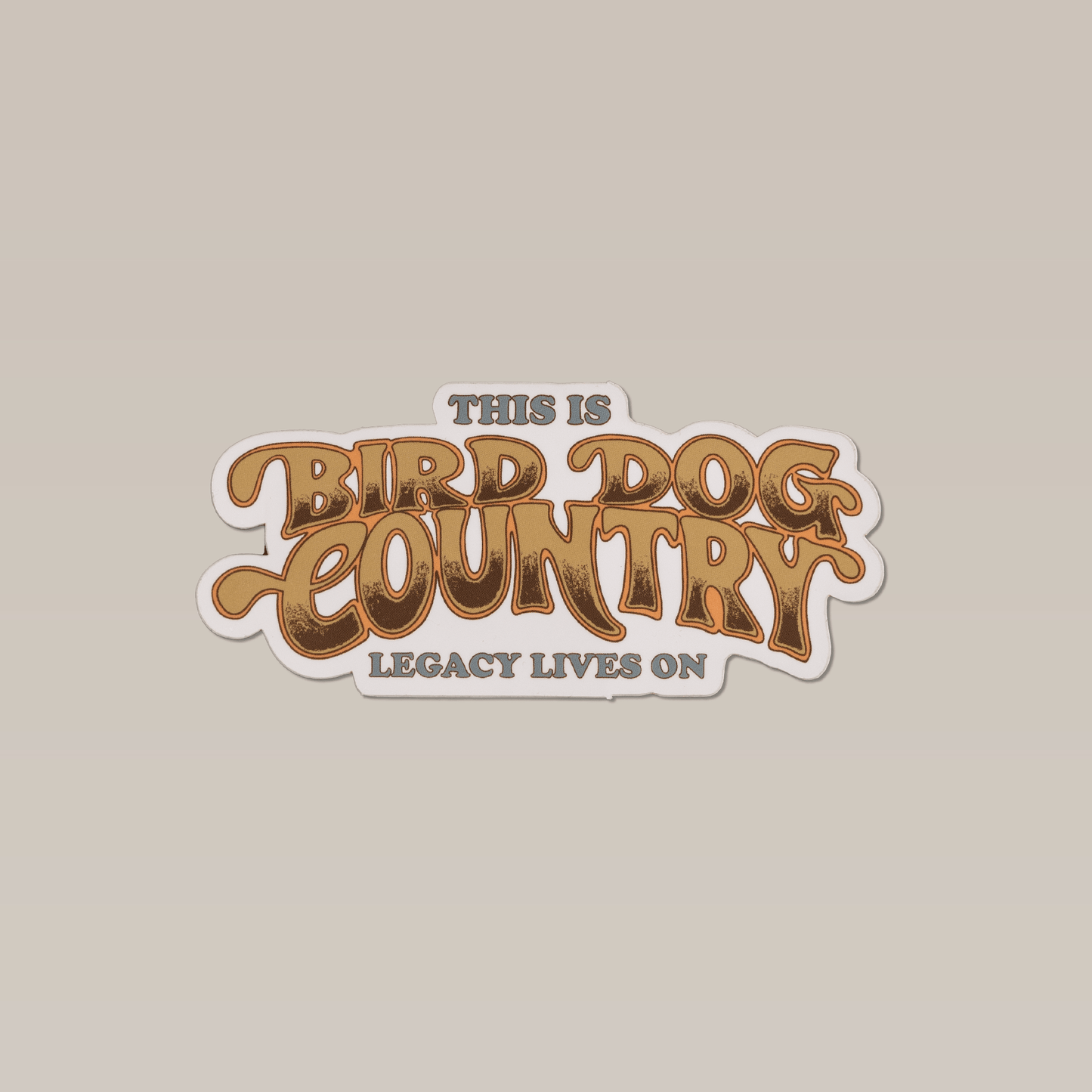 Bird Dog Country sticker by Ballad of the Bird Dog features gold, retro-style text "This is Bird Dog Country" and smaller grey "Legacy Lives On" on a light beige background—ideal for fans of bird dog culture.