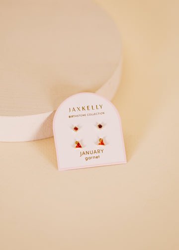 JaxKelly Birthstone Earrings for January feature garnet stones and hypoallergenic sterling silver posts, displayed on a “Birthstone Collection January garnet” card against a beige background.