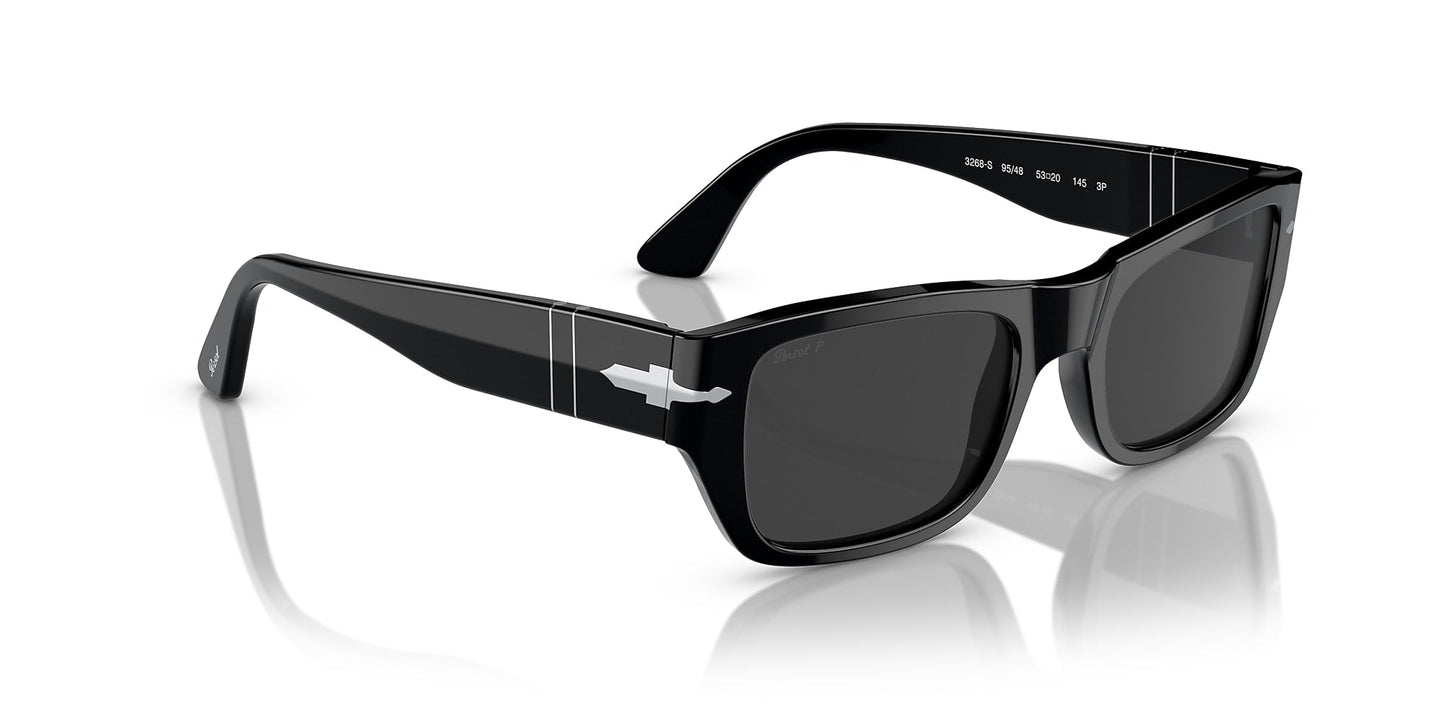 The Persol 0PO3268S Polar Black sunglasses feature thick black rectangular frames, silver arrow details, and dark lenses, offering glam rock and vintage style as they rest on a glossy white surface.
