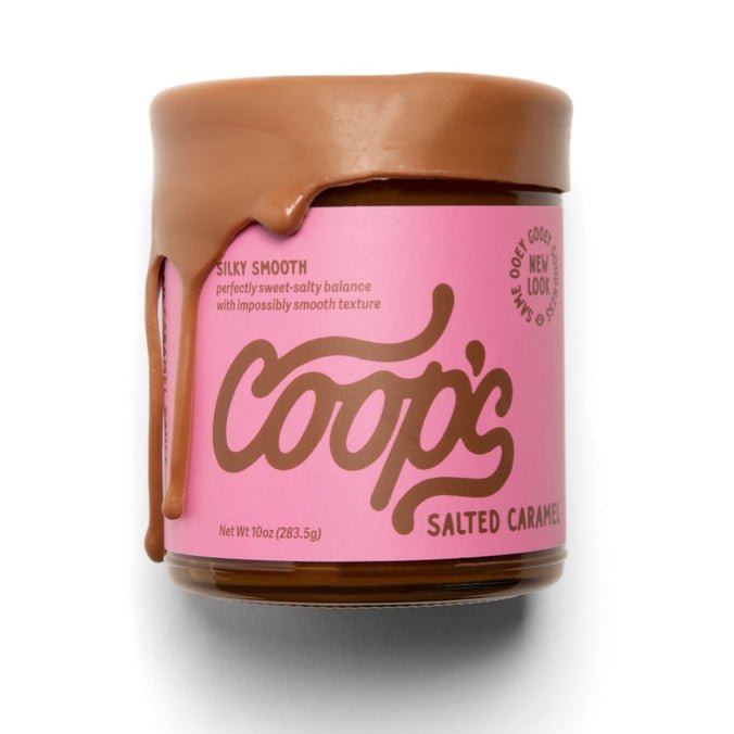 A jar of Coop's Salted Caramel with rich caramel dripping over the lid, featuring a pink label with product details and Coop's small batch caramel branding.