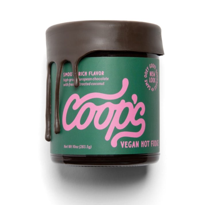 A jar of Coop's Vegan Hot Chocolate, a rich dairy-free ice cream topping with chocolate dripping down the side, features a green label with pink text.