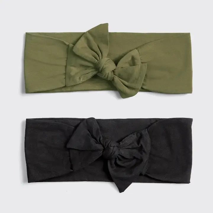 The KITSCH Cotton Adjustable Headband 2pc set features one olive green and one black headband, each with a large knot bow, displayed on a light gray background. These eco-friendly bands blend comfort and style.