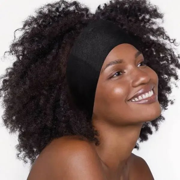 A woman with natural curly hair smiles and looks off to the side, wearing a KITSCH Cotton Adjustable Headband 2pc against a plain background.