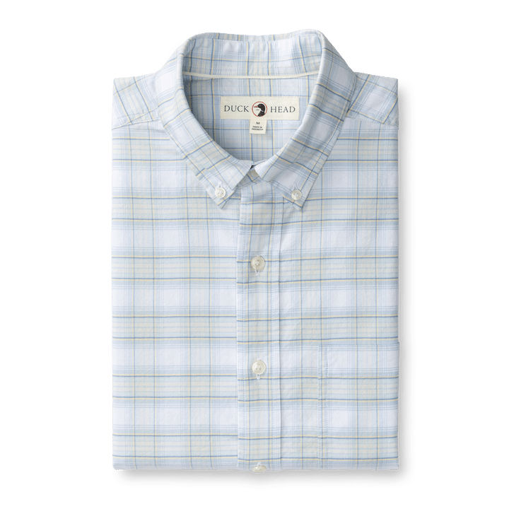 The Duck Head Cotton Oxford Sport Shirt in Raney Plaid features a folded, light blue plaid design with visible collar and neck label, offering classic style and comfort.
