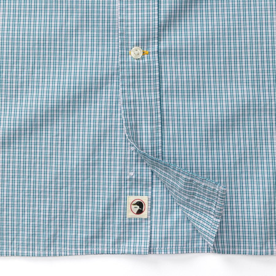 Close-up of the Duck Head Cotton Poplin Sport Shirt in Ferry Plaid, featuring blue and white checkered poplin, white buttons, a small face label near the hem, and garment-washed for extra softness and easy care.