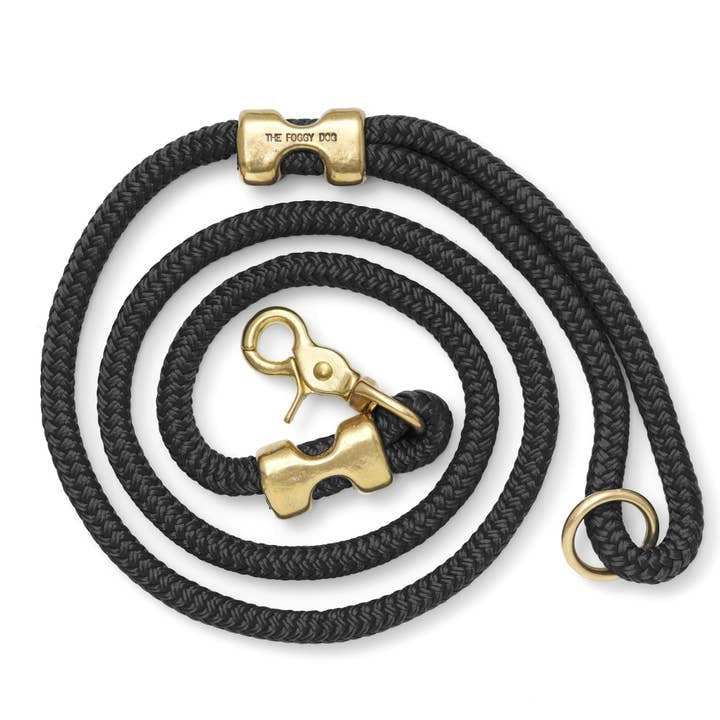 The Foggy Dog's coiled black Dog Leash features double-braided marine rope and gold solid brass hardware—including a clasp, ring, and an engraved piece with "THE FOGGY DOG.