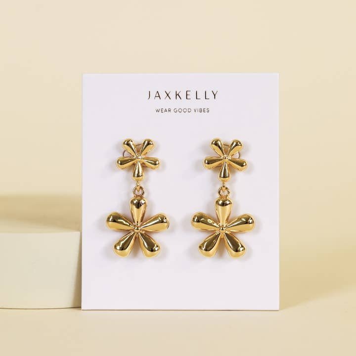 A pair of JaxKelly Double Daisy Earrings, hypoallergenic and tarnish-free, displayed on a branded card against a neutral background.