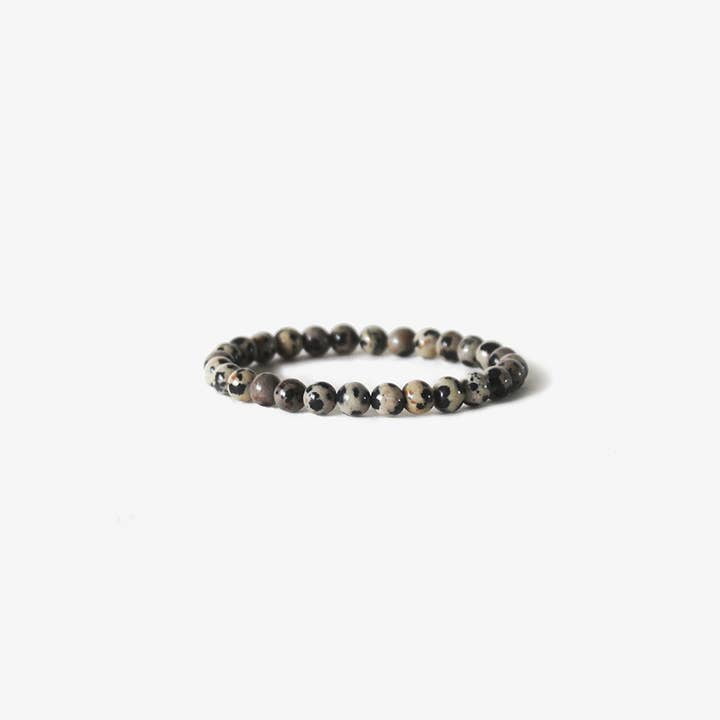 The Earth Bracelet - Dalmatian Stone by BRANCO features round, speckled gemstones arranged in a circle and is displayed on a plain white background.