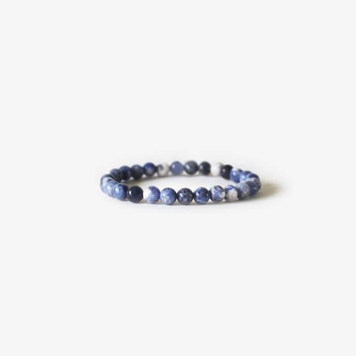 The Earth Bracelet - Indigo Sodalite by BRANCO features round blue and white marbled sodalite stones, arranged in a circle and displayed on a plain white background.