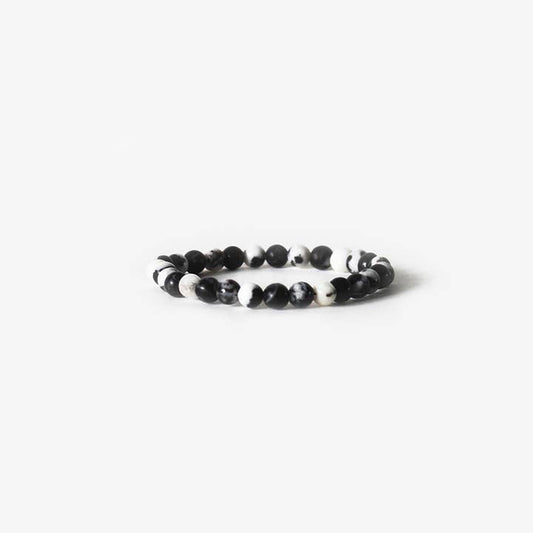 The Earth Bracelet - Zebra Jasper by BRANCO showcases alternating black and white round beads in a single strand, displayed on a plain white background. This gemstone bracelet adds natural style to any outfit.