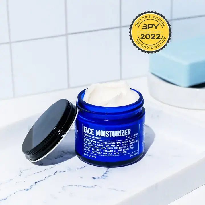 The open Face Moisturizer | Blu Atlas, in a blue jar with a black lid, rests on white tiles. An "Editor's Choice 2022" badge highlights its nourishing formula by Blu Atlas for dry skin.