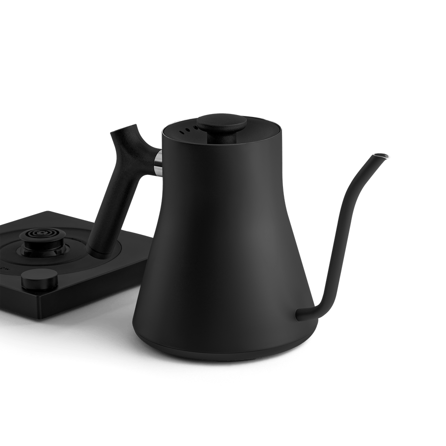 The Fellow Electric Kettle features a matte black finish, precision pour spout, and matching base for optimal temperature control, shown on a plain background.