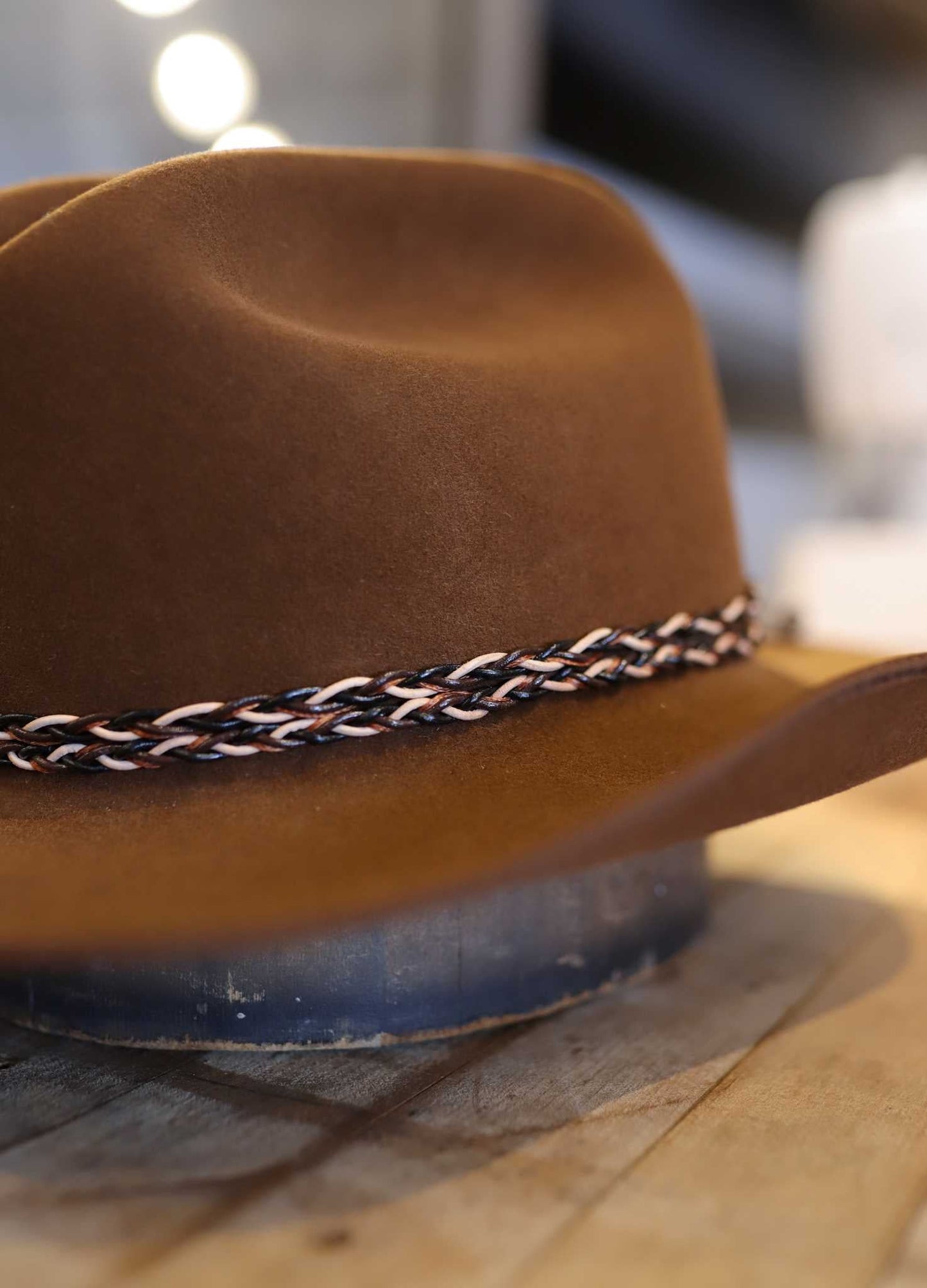 The Easy Drifter Felt Hat | Whiskey LBJ sits on a wooden surface, showcasing its classic LBJ-inspired style and braided band.