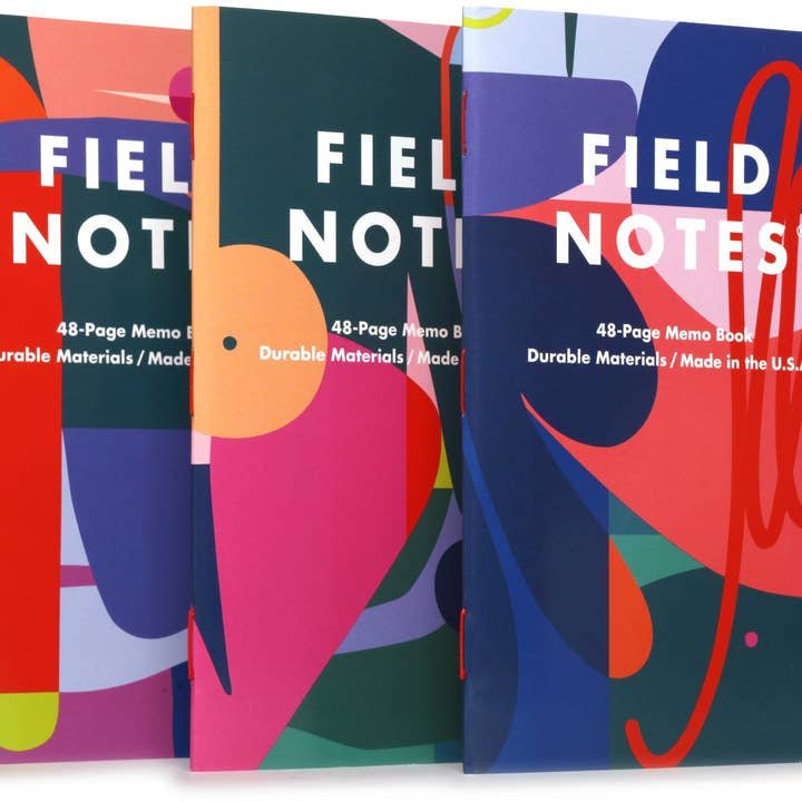 Three vibrant Flora | Field Notes memo books by Field Notes, featuring abstract covers inspired by the Roman goddess of flowers and designed by Emmy Star Brown, stand upright and overlap in a colorful display.