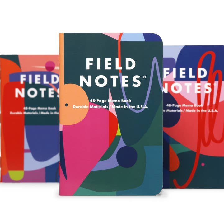 Three Flora | Field Notes Memo Books by Field Notes—featuring abstract, colorful covers designed by Emmy Star Brown and inspired by the Roman goddess of flowers—are shown side by side, with the center notebook standing upright.