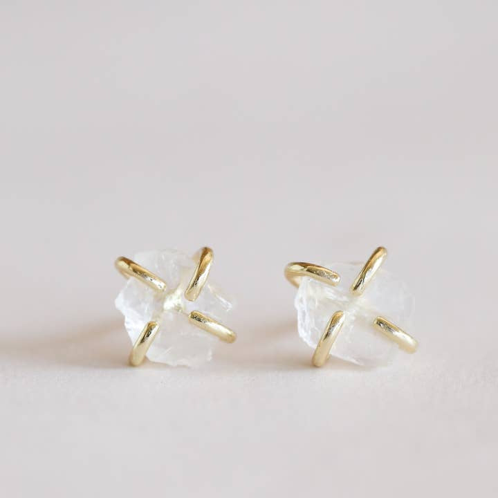 The JaxKelly Gemstone Prong Clear Quartz Gold Earrings feature raw clear quartz stones in four-prong gold settings. Hypoallergenic and perfect for everyday wear, these stud earrings combine comfort and elegant design.