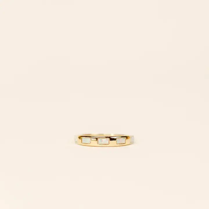 The JaxKelly Gold Ring features three white opal baguettes set in a tarnish-free gold band, shown against a plain beige background.