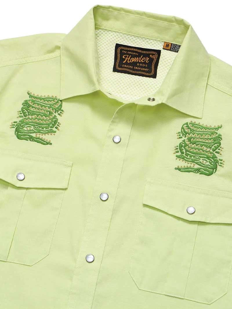 The Guacho Snapshirt | Slithering Gators by Howler Brothers is a light green shirt featuring two embroidered green snakes on the chest, dual flap chest pockets, and a branded tag inside the collar. Quick-drying for everyday comfort and style.