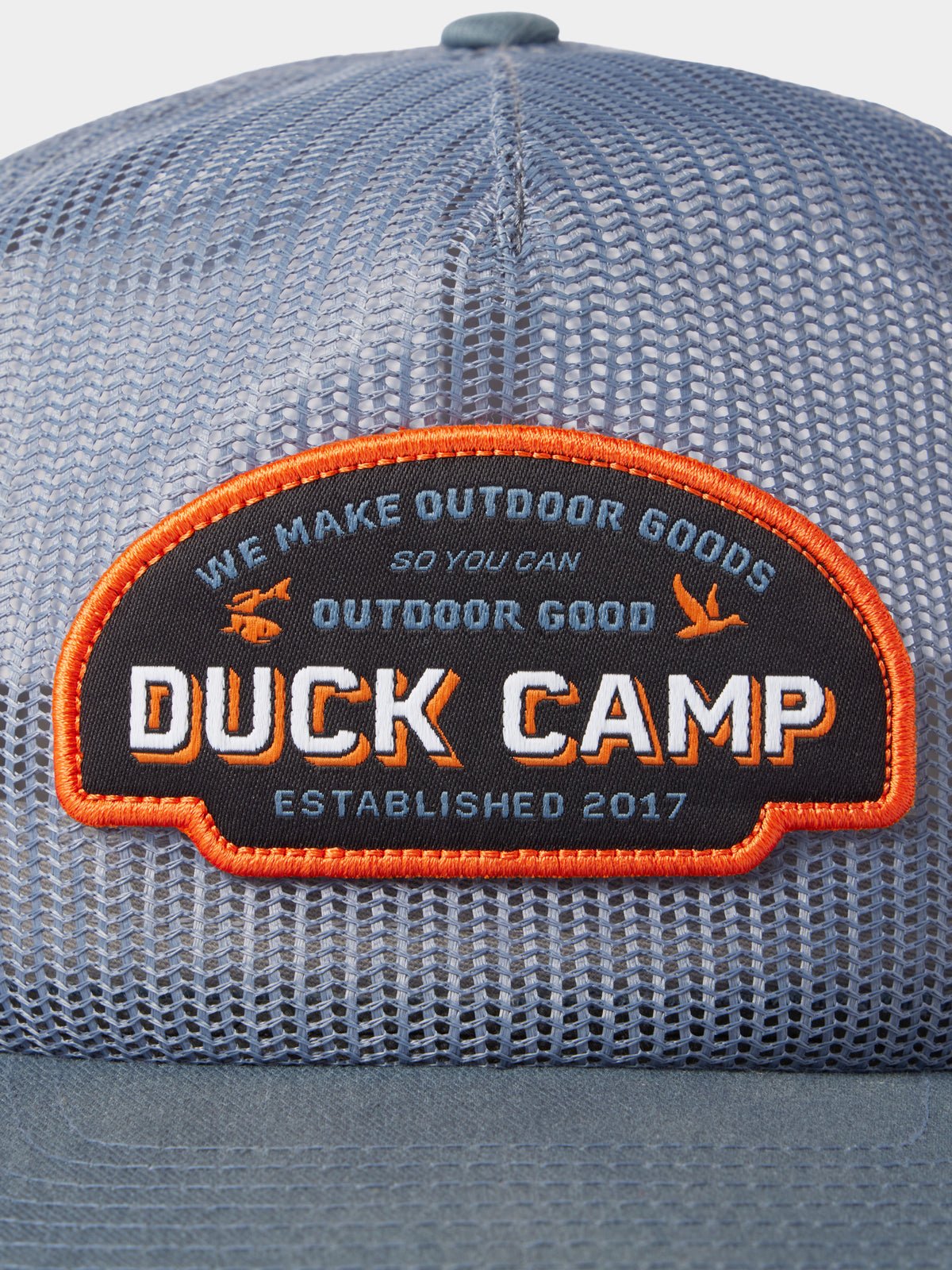 Close-up of the Duck Camp Gulf Trucker | Cast & Blast hat, a blue mesh adjustable snapback with a patch reading, "Duck Camp: We Make Outdoor Goods So You Can Outdoor Good, Established 2017.
