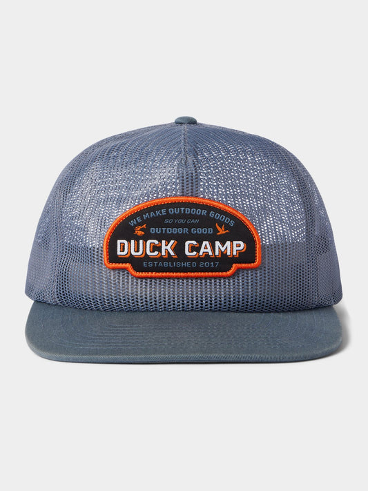 The Duck Camp Gulf Trucker | Cast & Blast is a breathable mesh hat with an adjustable snapback and a front patch reading "Duck Camp" and "We Make Outdoor Goods So You Can Outdoor Good. Established 2017.