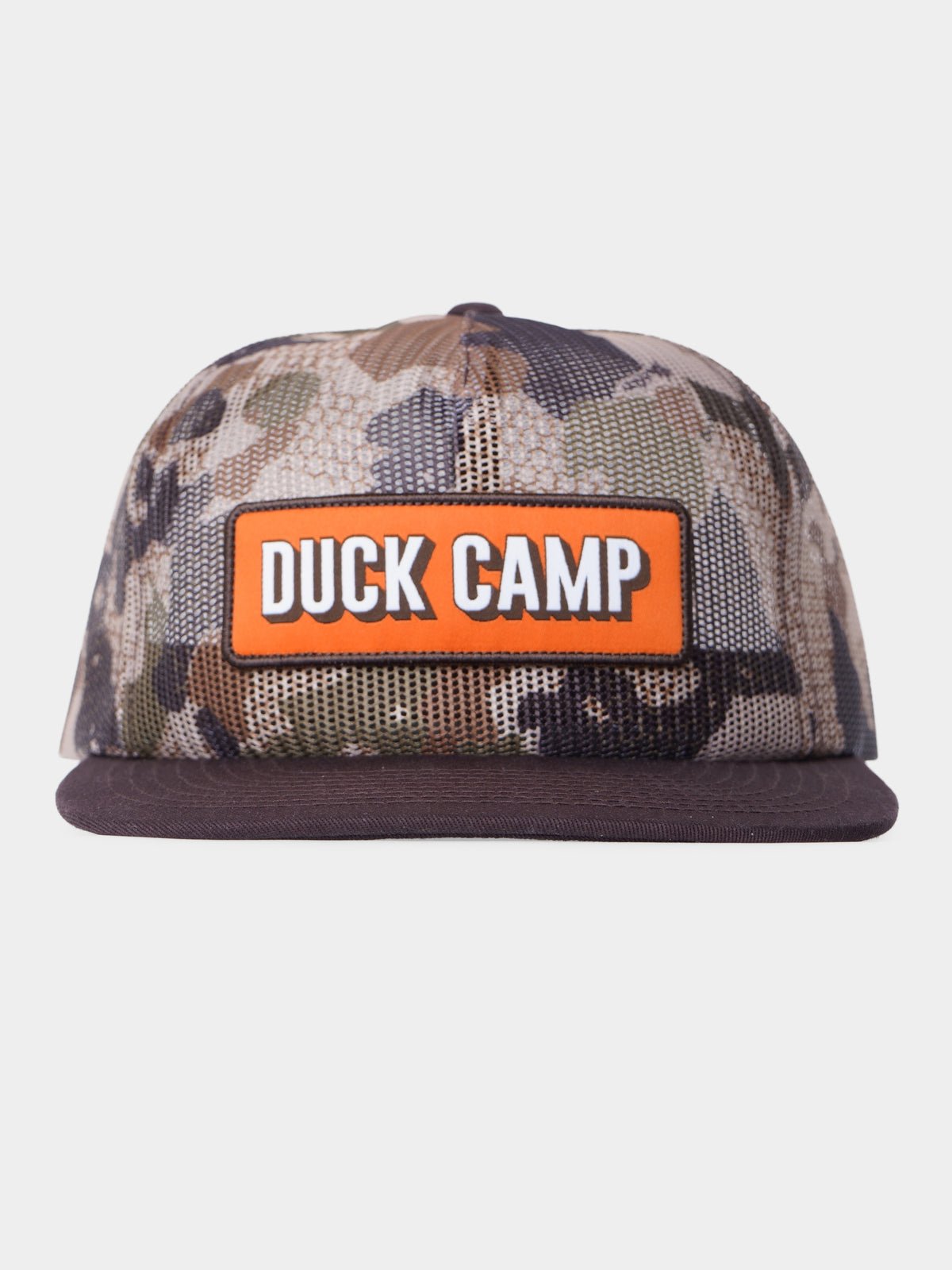 Duck Camp’s Gulf Trucker in Wetland features a camouflage design, flat brim, breathable mesh panels, and an orange front patch with "DUCK CAMP" in white letters.
