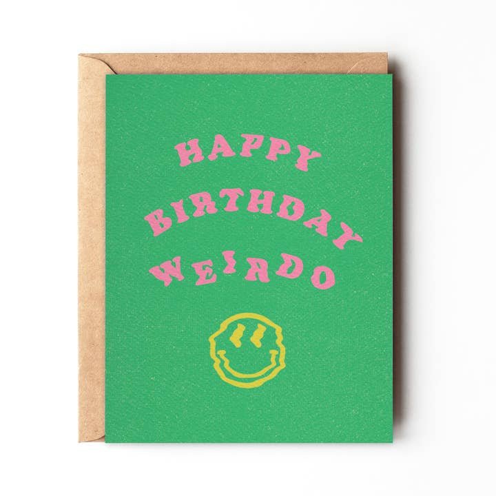 The "Happy Birthday Weirdo" card by Daydream Prints features bold pink text above a yellow smiley face on green cardstock and comes with a brown envelope. Designed in Portland, Oregon.