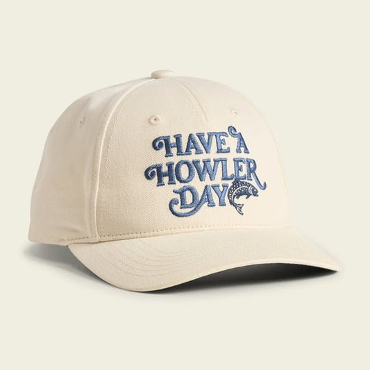 The Have a Howler Day cap by Howler Brothers features beige fabric, blue embroidered "Have A Howler Day" text, a small fish graphic, signature artwork on the front, and an adjustable snapback closure.