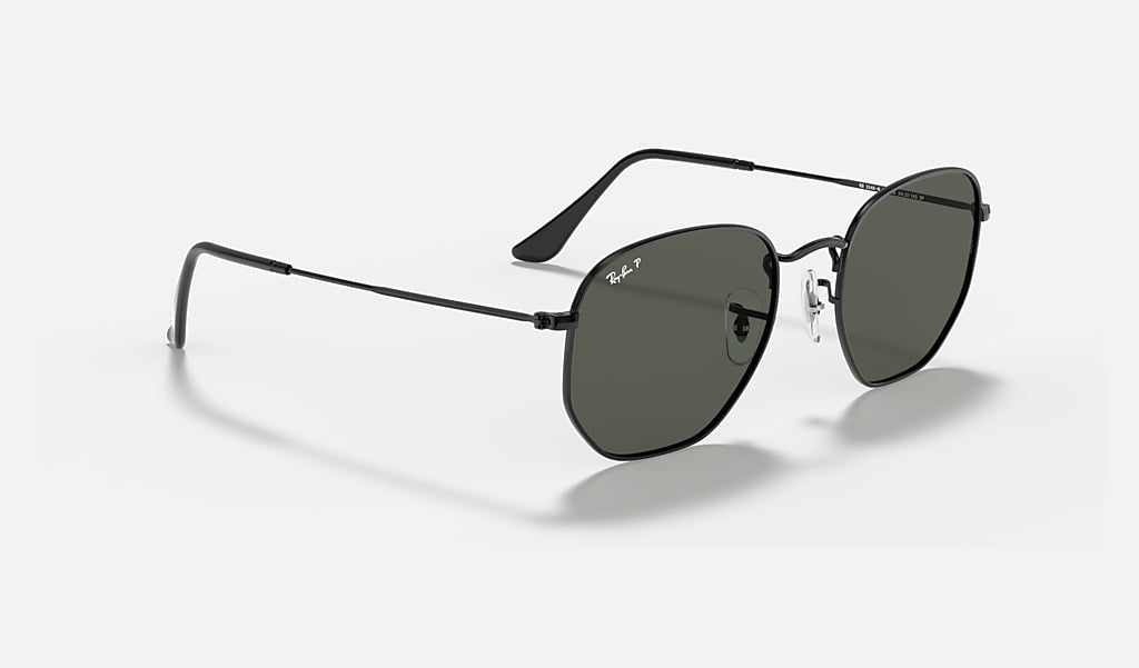 The Ray-Ban Hexagonal Flat Arista sunglasses, featuring green polarized lenses and a sleek black metal frame, are displayed on a plain white background.