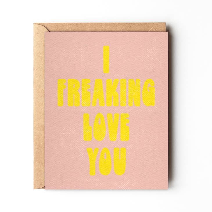 The "I Freaking Love You" greeting card by Daydream Prints features bold yellow text on a pink retro design and comes with a brown envelope.