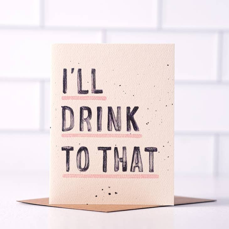 The "I'll Drink To That" greeting card by Daydream Prints features bold, underlined pink text and comes with a brown envelope—a fun, retro congratulations card for any occasion.