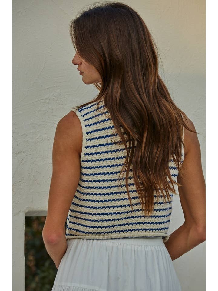 A woman with long brown hair stands facing away, wearing the By Together Knit Sweater Cotton Striped Buttondown V-Neck Vest paired with a white skirt.