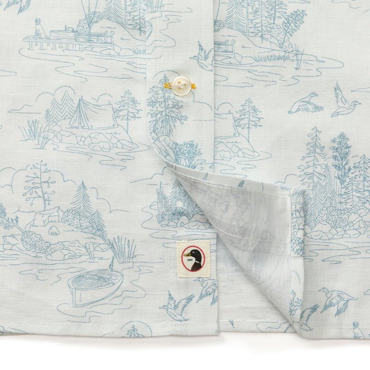 The Duck Head Linen Cotton Oxford Sport Shirt | Lakeview features light grey linen-cotton fabric with blue outdoor line art, button-down collar, garment-washed finish, and a bird logo patch near the hem.