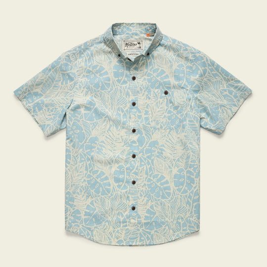 The Mansfield Shirt | Leafy Lithographs by Howler Brothers is a light blue short-sleeve button-up featuring a button-down collar, chest pocket, white tropical leaf print, dark buttons, and is crafted from lightweight cotton-poly blend.