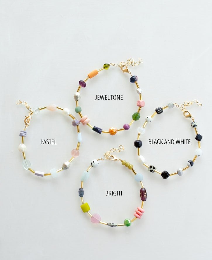 Four Mariposa Bracelets by Jill Makes—pastel, jewel tone, black and white, and bright—are displayed on a white surface, each adorned with colorful gemstone beads for a vibrant accent.