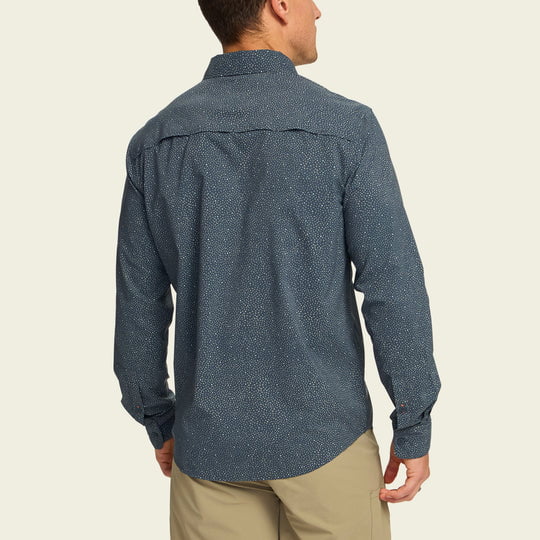 A man faces away from the camera, wearing Howler Brothers’ Matagorda Long Sleeve Lotsa Dots shirt with UPF 35 sun protection and light khaki pants.