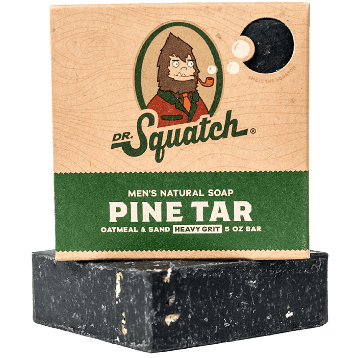 A box of Dr.Squatch Pine Tar Soap sits above a rugged, gritty black bar. The packaging showcases a cartoon Bigfoot and product info, highlighting the woodsy, natural appeal of this men’s soap from Dr.Squatch.