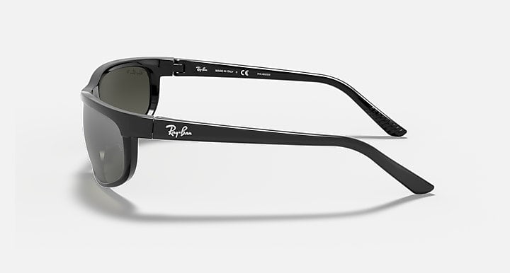 Ray-Ban Predator 2 sunglasses in black with dark grey lenses are shown from the side, featuring sporty temple tips and a Ray-Ban logo on the temple, set against a plain light background.