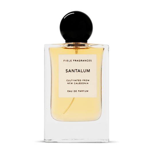 A clear glass bottle with a black cap holds yellow liquid. The label reads: "Santalum | Fiele Fragrances" by Fiele Fragrance, a vegan, cruelty-free eau de parfum.