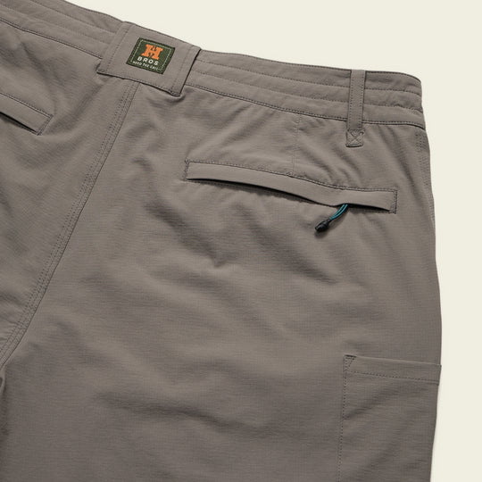 Close-up of the back of Shoalwater Tech Shorts by Howler Brothers in gray, featuring two back pockets (one with a zipper and pull tab), a brand label on the waistband, and quick-dry fabric for all-day comfort.