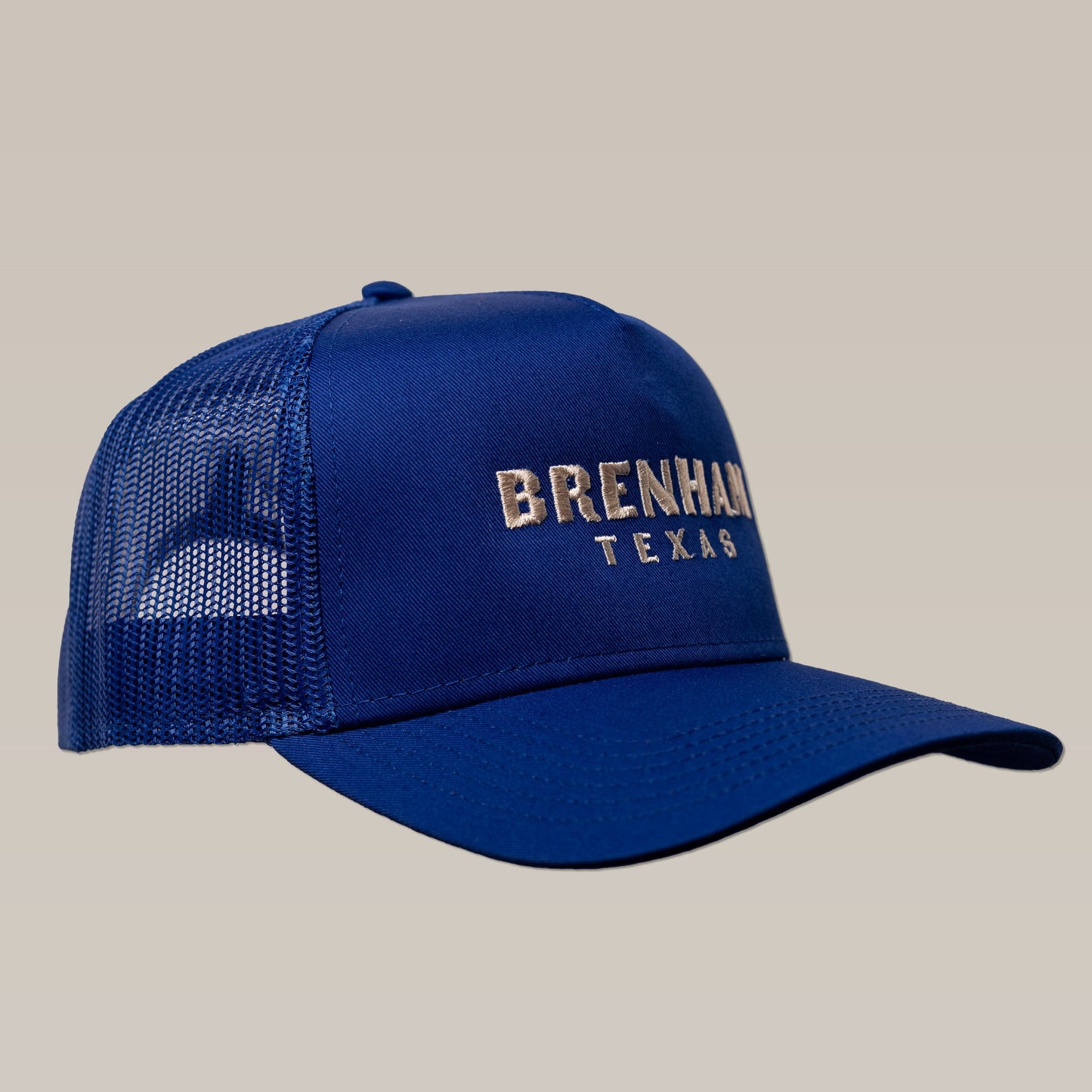 The Shop Hat | Brenham Varsity by Ballad of the Bird Dog is a blue mesh trucker cap with "Brenham Texas" embroidered in white on the front panel, shown against a plain background.