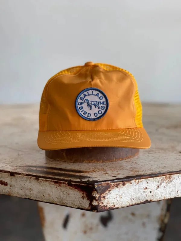 A Shop Hat | Circle Clubhouse Tradition by Ballad of the Bird Dog, featuring a circle logo patch, sits on a table.