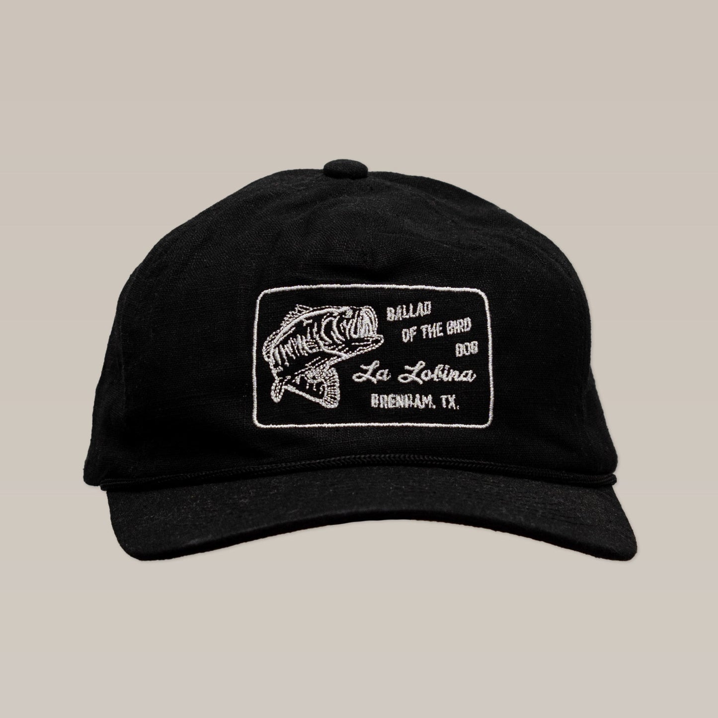 The Ballad of the Bird Dog Shop Hat | La Lobina is a black angler hat with a white embroidered fish patch and "Ballad of the Bird Dog" branding.