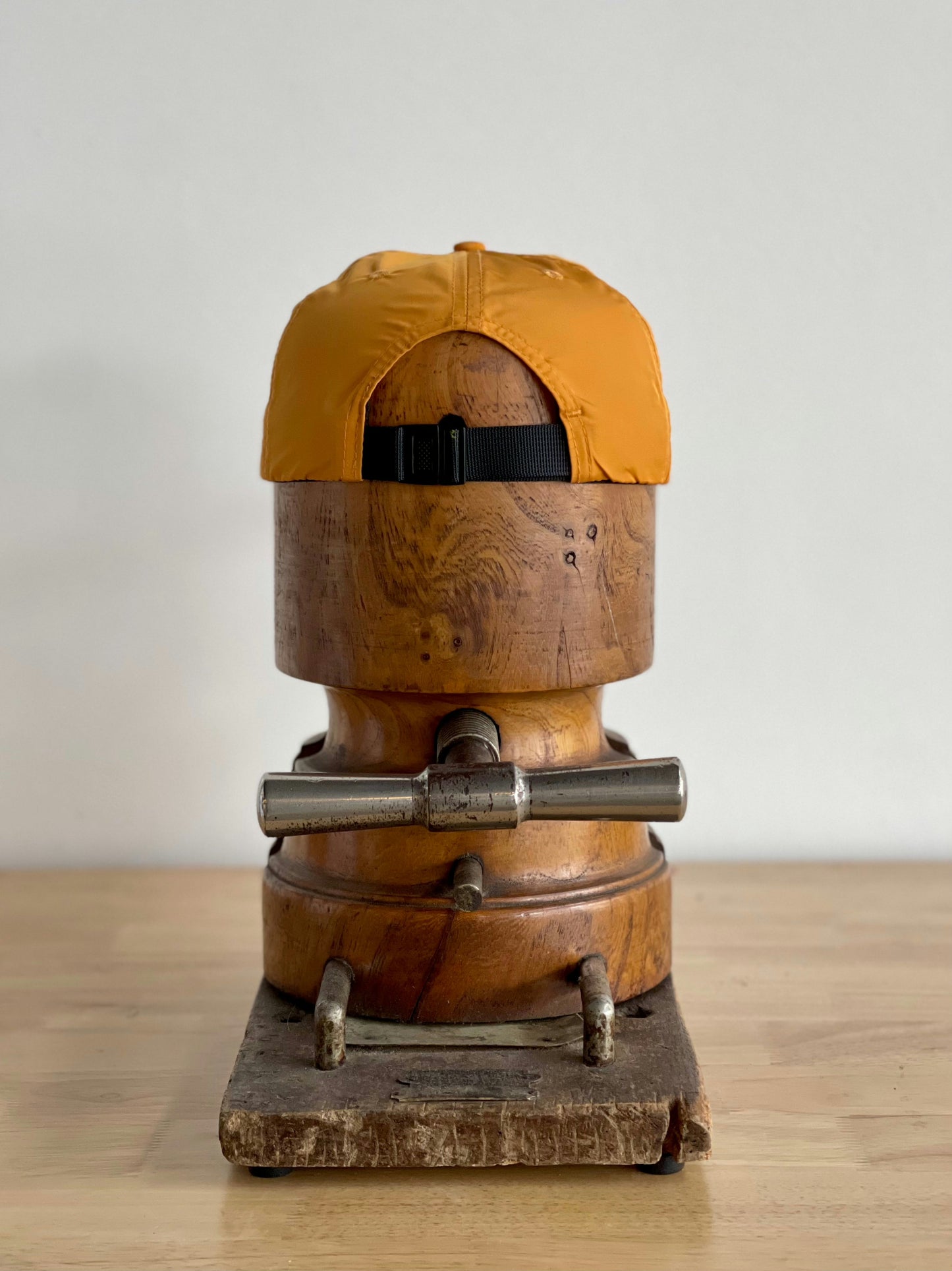The Shop Hat | Neon Revival by Ballad of the Bird Dog is shown backwards on a wooden hat block with metal clamps, set on a light wood surface against a plain background.