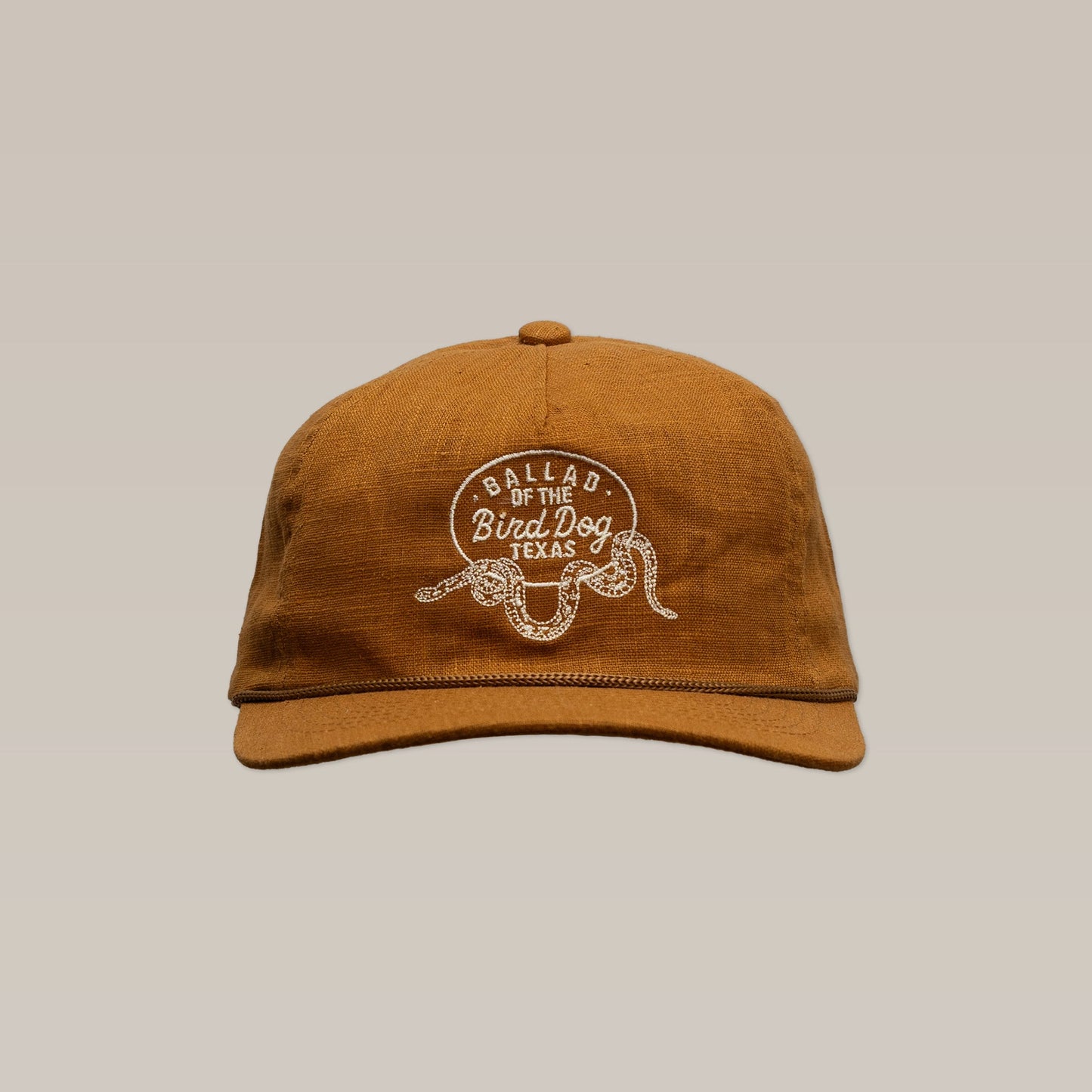 The Shop Hat | Rattlesnake Oval Logo by Ballad of the Bird Dog is a brown, snake-themed hat with "Ballad of the Bird Dog Texas" and a snake embroidered on the front, handcrafted in Brenham, TX.